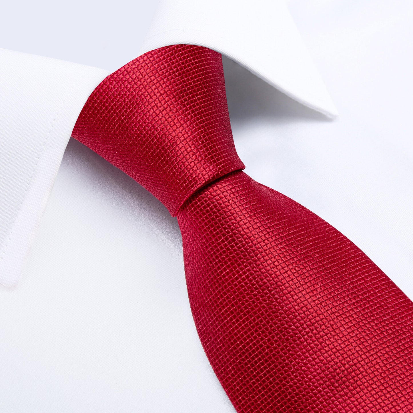 “Red Texture silk tie on a crisp white dress shit laid flat, showing detailed weave and pattern on a white background.”