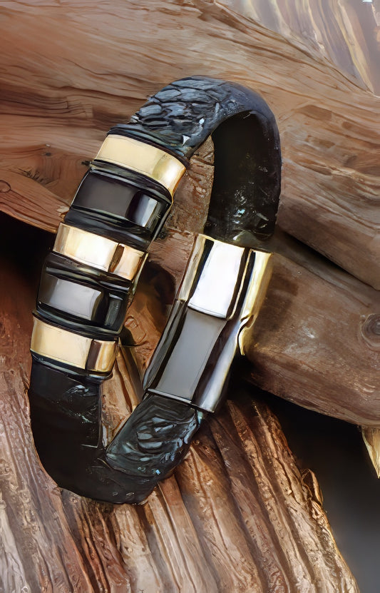 A sleek black braided leather men's bracelet with gold and black steel accent rings.
